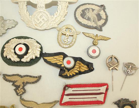 A collection of various German Third Reich cap badges, cloth badges and pins